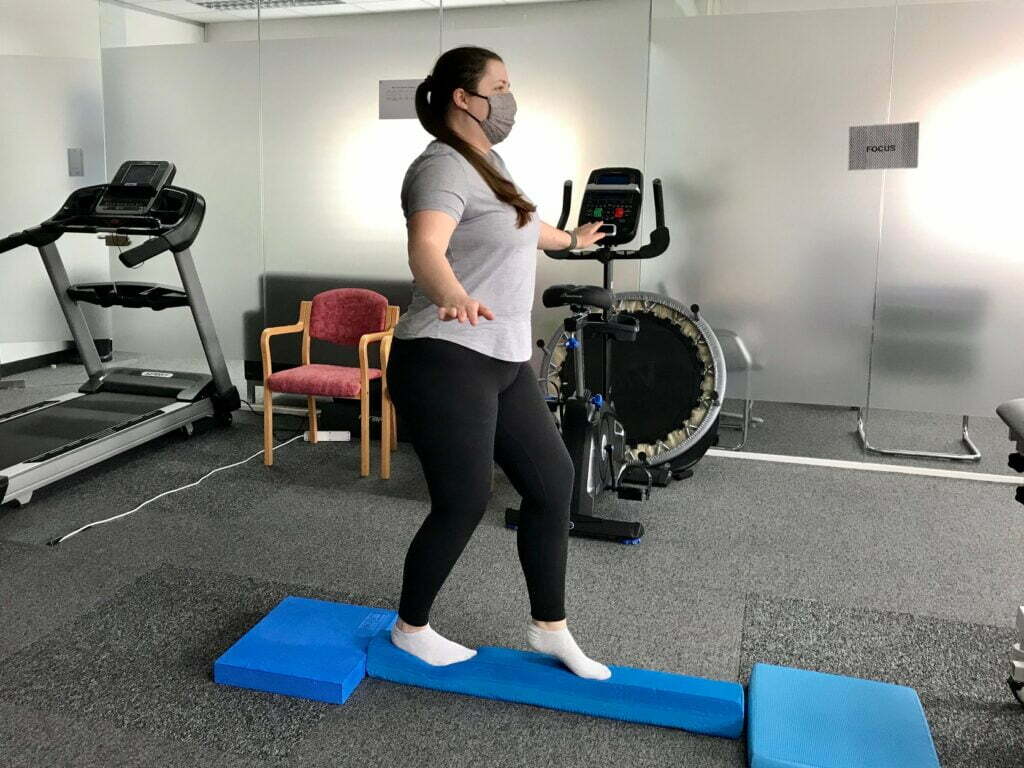 Patient on balancing beam as part of neurological concussion rehabilitation