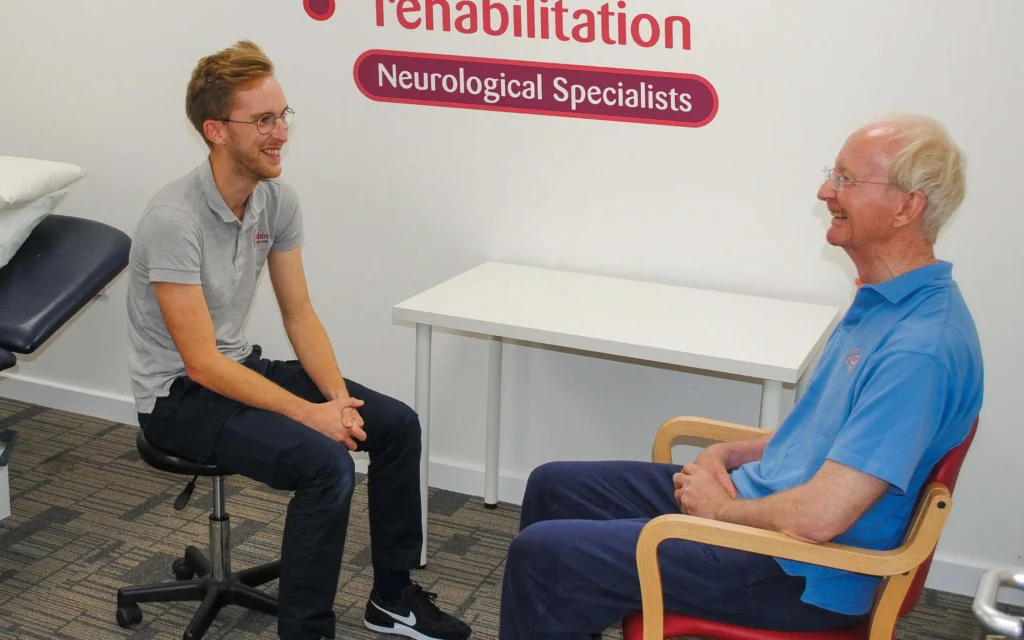 Physiotherapist and patient sat facing towards each other, participating in an assessment consultation